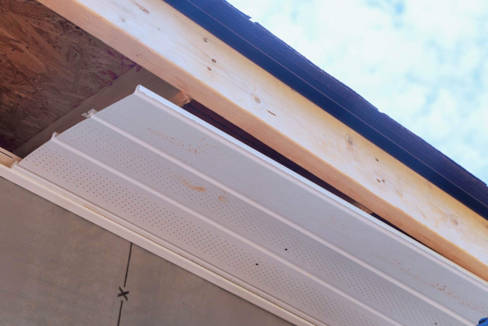 Worker installation of upvc soffit boards on roof corners ceiling rafters a house